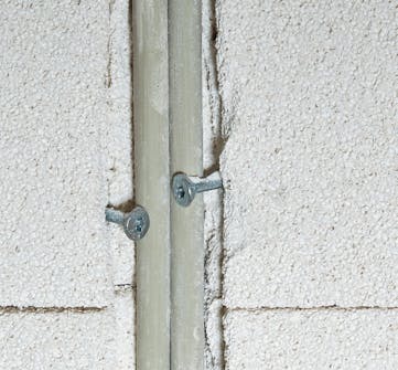 Isolering af kældervæg: Kablerne, som elektrikeren har trukket, er gjort fast Isolering af kældervæg: Kablerne, som elektrikeren har trukket, er gjort fast